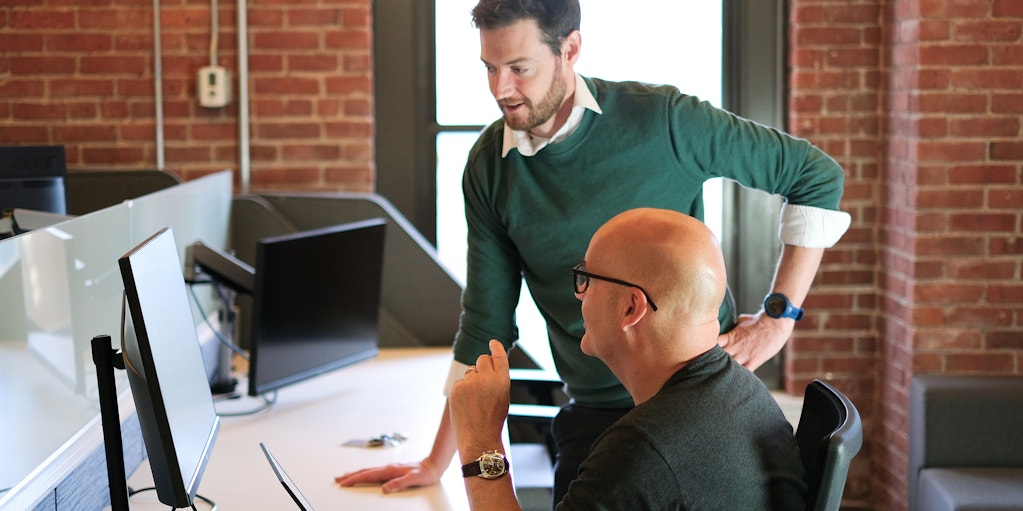 Charlie Paterson discussing work at a computer with colleague