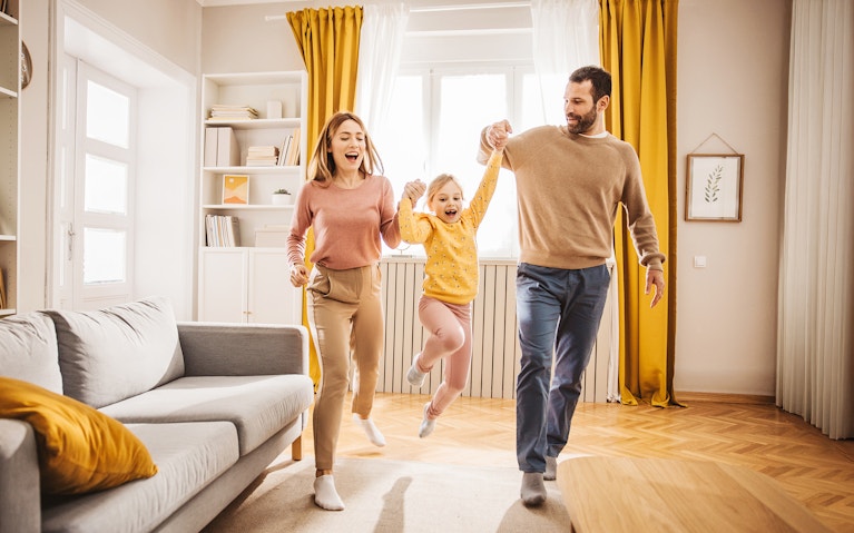 Parents picking up child in sunny room
