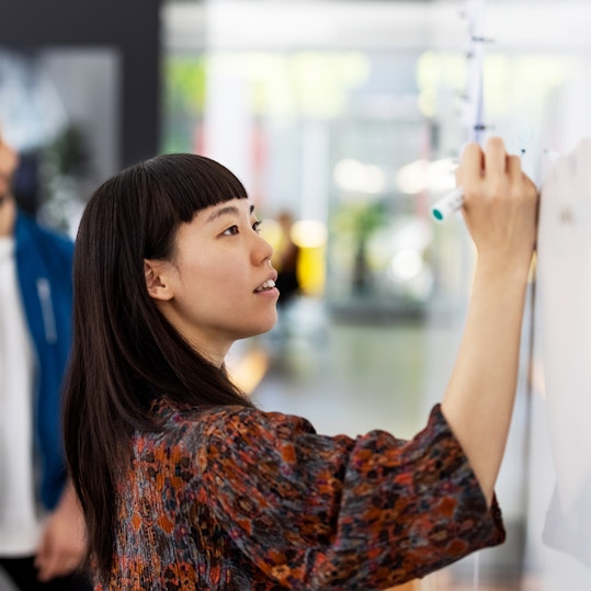 Three colleagues working together at a whiteboard