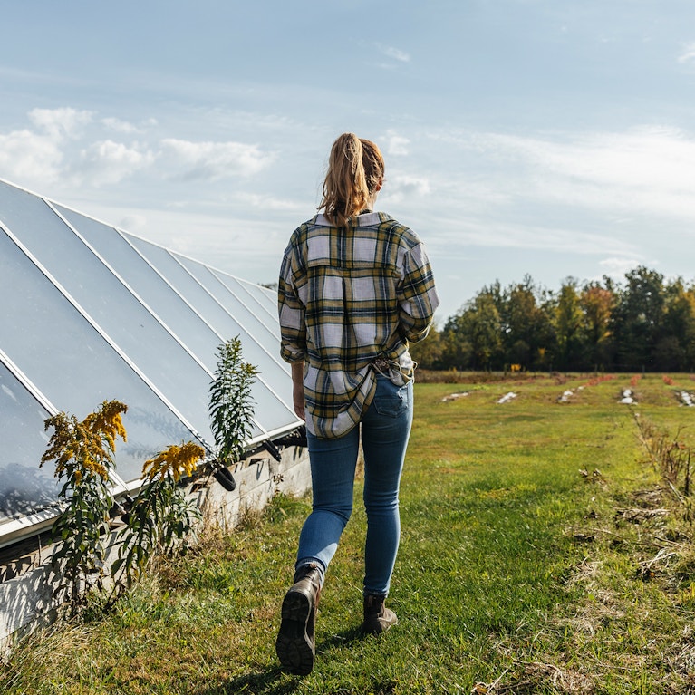 Farmer walking past greenhouse towards field