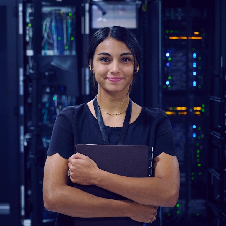 IT technician in server room holding laptop computer