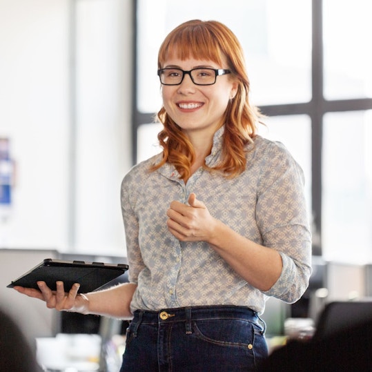 A woman standing up speaking in an office room.