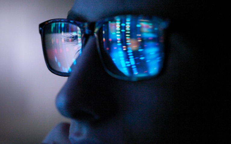 Genetic research, computer screen reflection in spectacles of DNA profile, close up of face