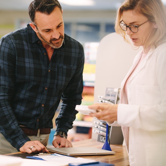 Pharmacist showing medicine to customer in pharmacy