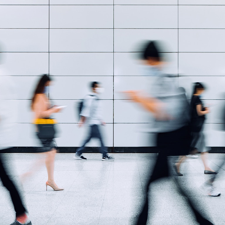 Crowd of busy commuters with protective face mask walking through platforms at subway station during office peak hours in the city