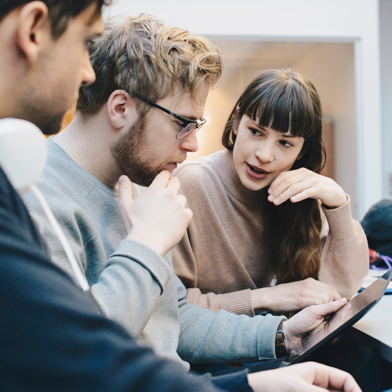 Male and female computer programmers discussing over digital tablet at desk in office