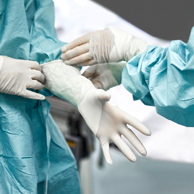 Female doctor helping surgeon wearing glove