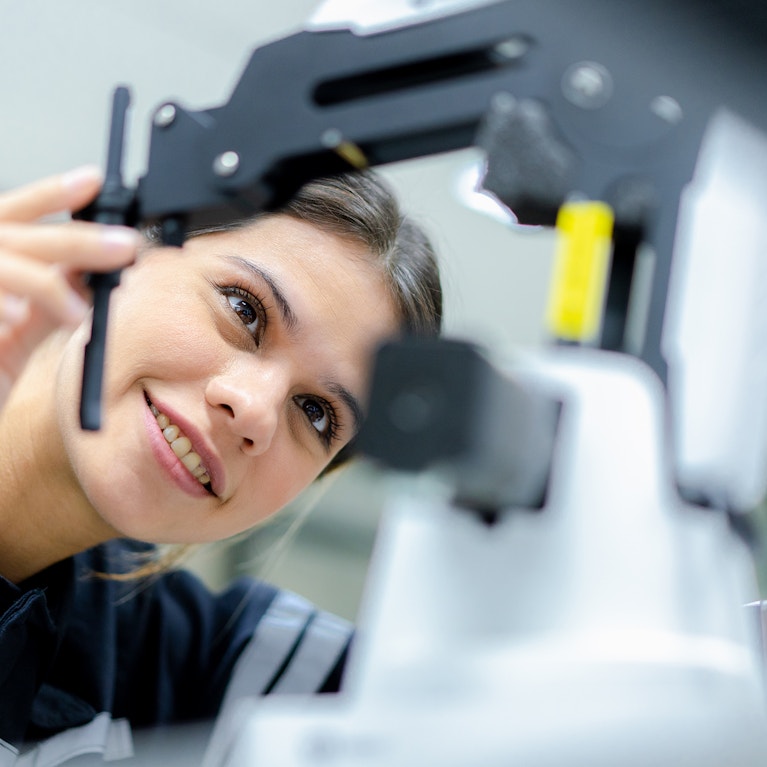 Female engineer training write a program control robot and robot arm in classroom