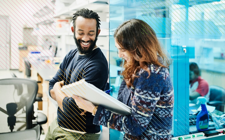 Two people in an office smiling and talking to each other