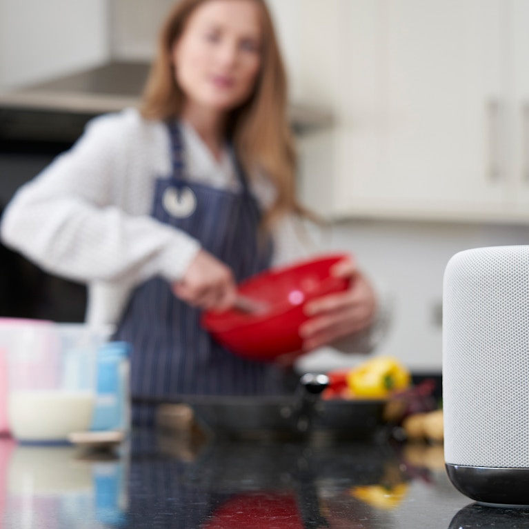 Woman preparing meal at home asking digital assistant question