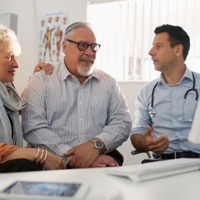 Older couple looking at computer screen while talking to doctor