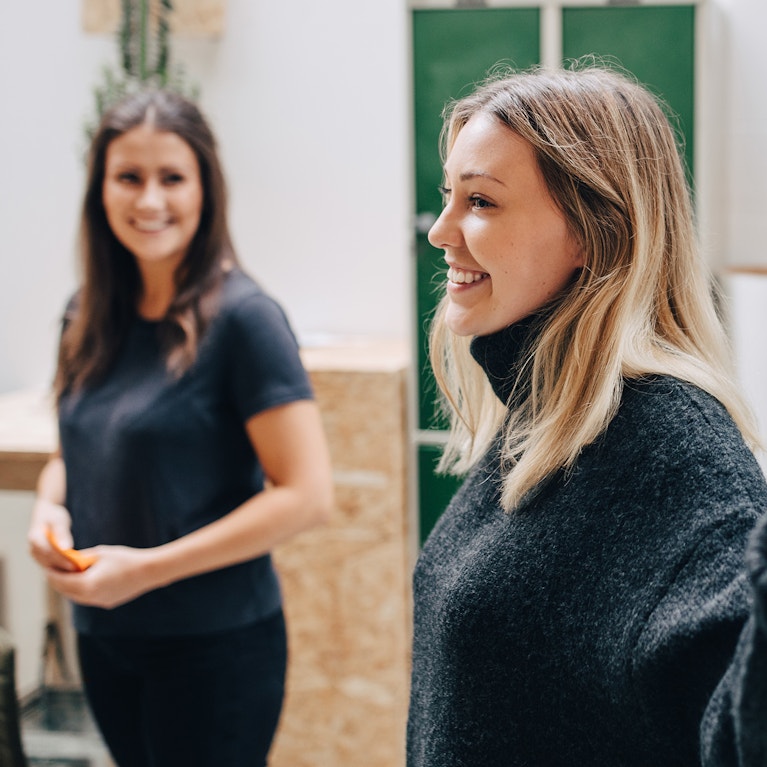 Side view of smiling businesswoman explaining adhesive notes stuck on glass wall in meeting