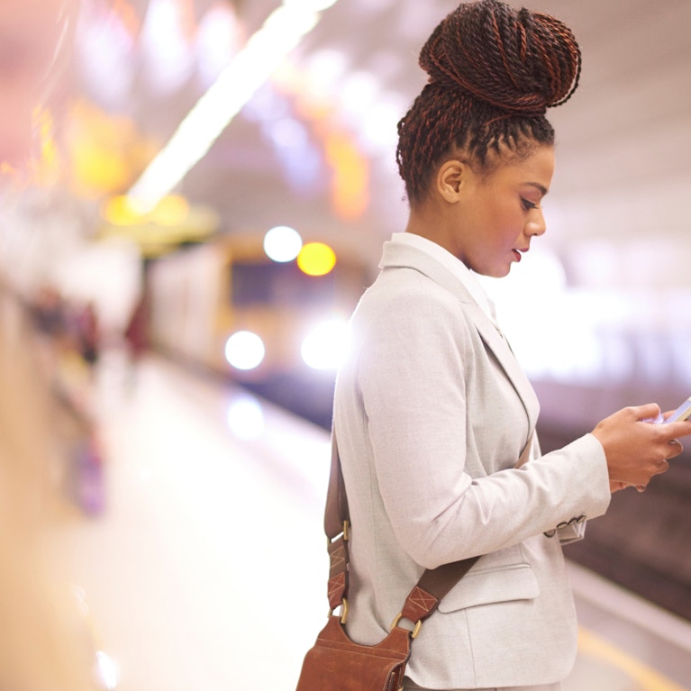 Businesswoman using mobile device on train platform