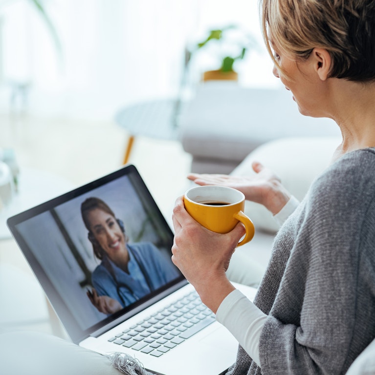 Woman using laptop and having video call with her doctor while sitting at home.
