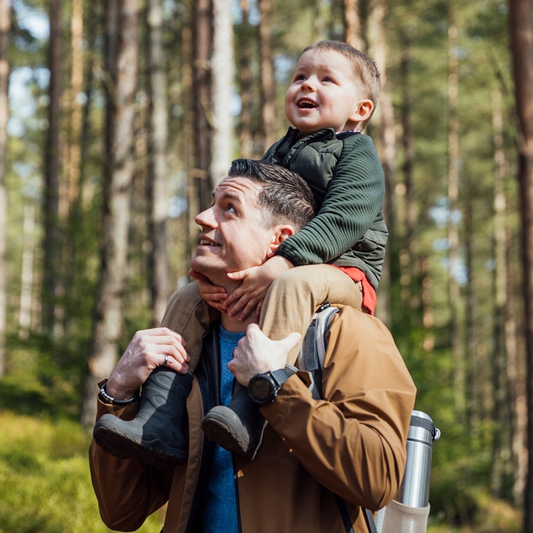 Father and child walking through a green wooded forest